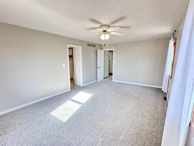 unfurnished bedroom with carpet flooring, a barn door, ceiling fan, and a textured ceiling