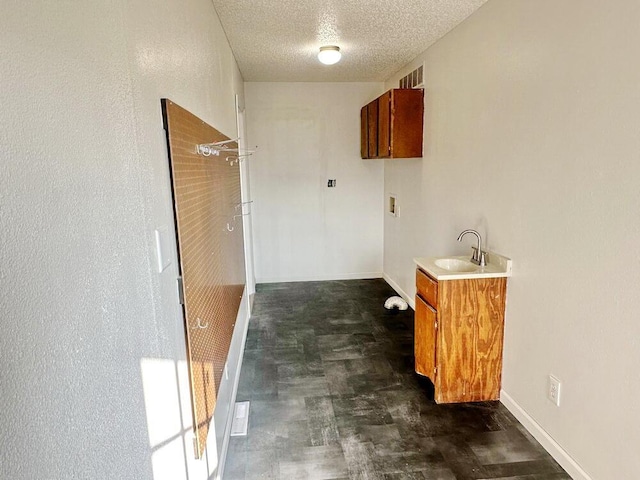 washroom with hookup for a washing machine, sink, cabinets, and a textured ceiling