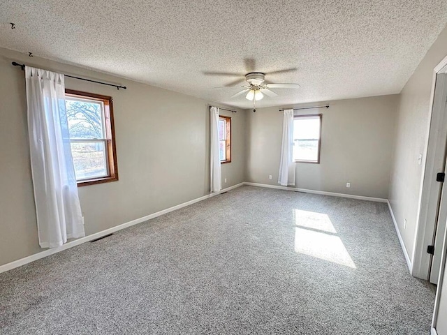 spare room with carpet flooring, a textured ceiling, plenty of natural light, and ceiling fan