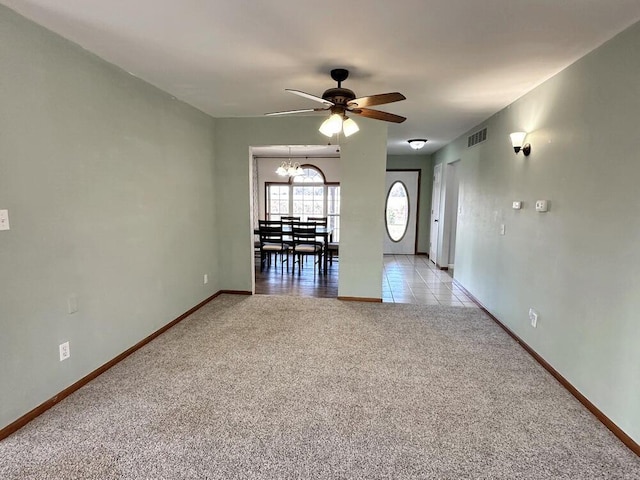 carpeted empty room featuring ceiling fan with notable chandelier