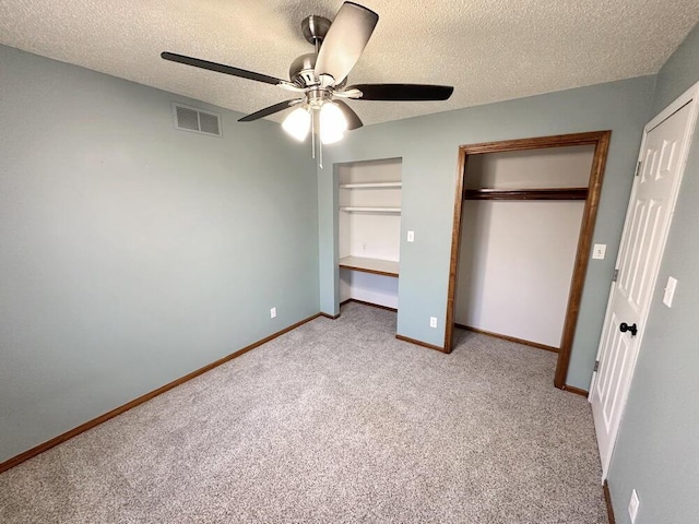 unfurnished bedroom featuring ceiling fan, light colored carpet, a textured ceiling, and a closet