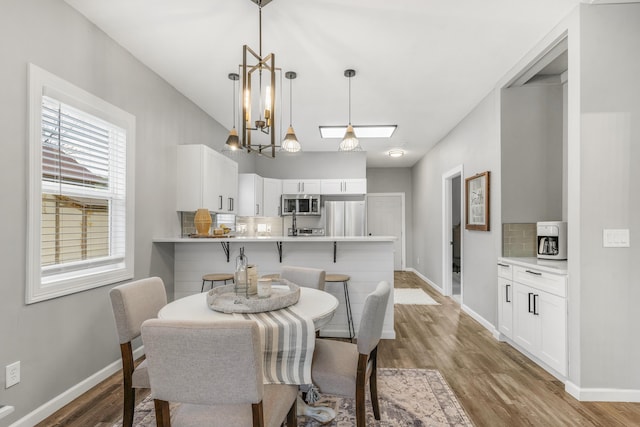 dining space featuring wood-type flooring and an inviting chandelier