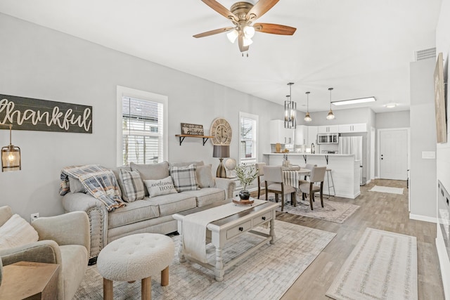 living room with ceiling fan and light hardwood / wood-style flooring