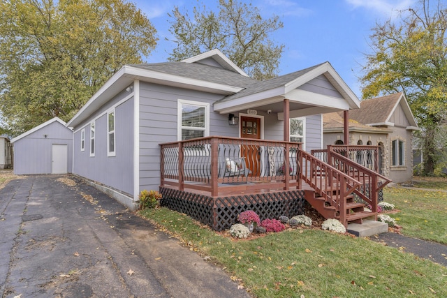 view of front of home with a storage unit, a front yard, and a wooden deck