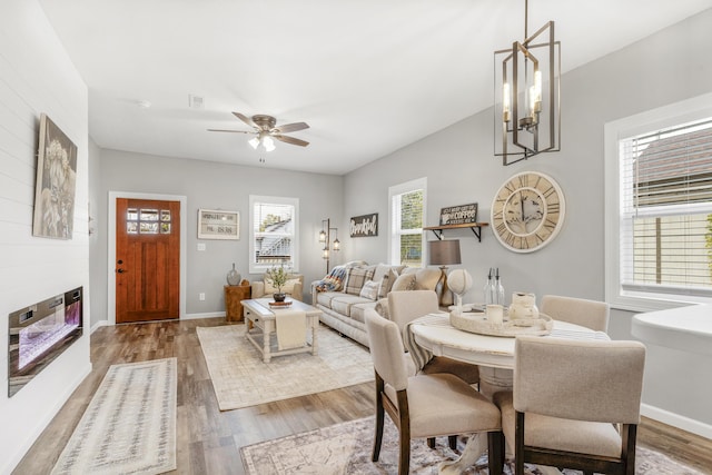 dining area with ceiling fan with notable chandelier and light hardwood / wood-style floors