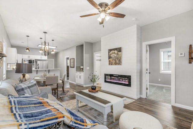 living room featuring a fireplace, dark hardwood / wood-style flooring, and ceiling fan with notable chandelier