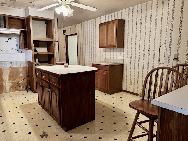 kitchen with ceiling fan, dark brown cabinets, and a kitchen island