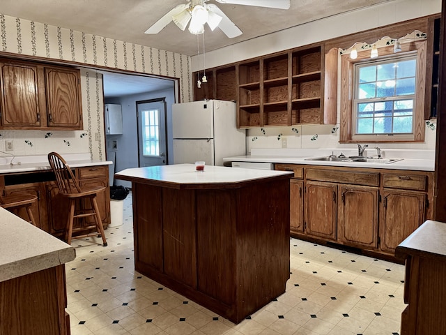 kitchen featuring ceiling fan, a center island, sink, white fridge, and decorative backsplash