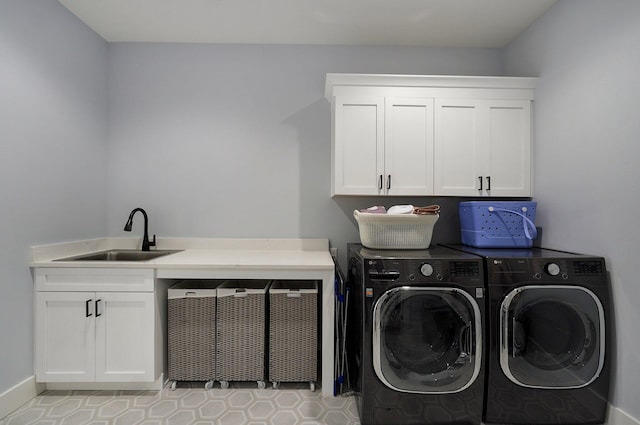 clothes washing area with separate washer and dryer, sink, and cabinets