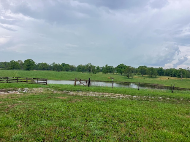 view of yard with fence, a rural view, and a water view