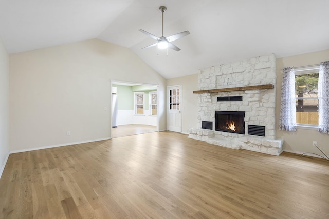 unfurnished living room with vaulted ceiling, light hardwood / wood-style floors, a stone fireplace, and ceiling fan