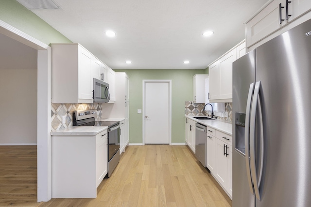 kitchen featuring appliances with stainless steel finishes, backsplash, white cabinetry, and sink