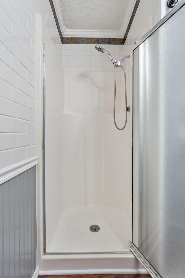 bathroom featuring a textured ceiling, walk in shower, and crown molding