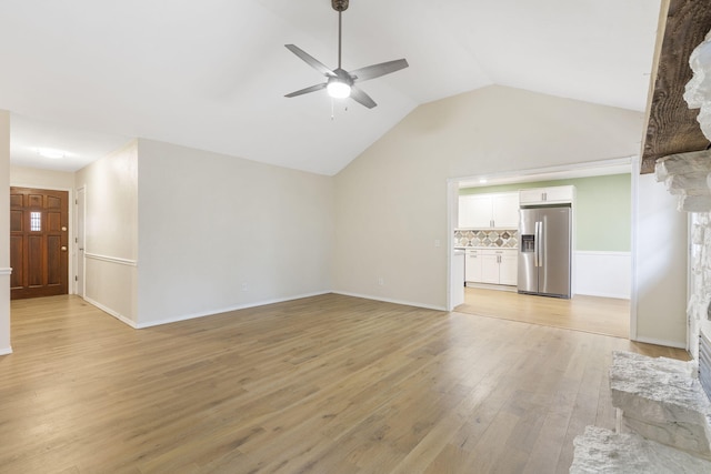 unfurnished living room featuring vaulted ceiling, light hardwood / wood-style flooring, ceiling fan, and a stone fireplace