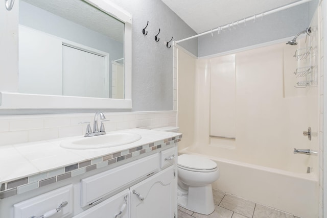 full bathroom with vanity, tile patterned floors, washtub / shower combination, toilet, and tasteful backsplash