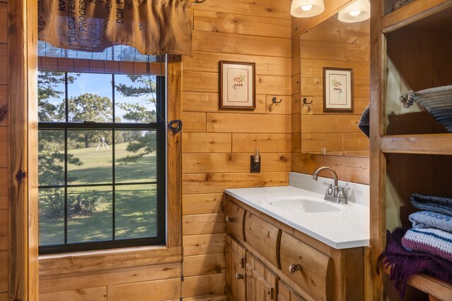 bathroom featuring a healthy amount of sunlight, vanity, and wood walls