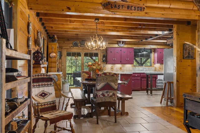 dining space featuring an inviting chandelier, sink, and wood walls