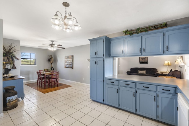 kitchen with blue cabinetry, ceiling fan with notable chandelier, hanging light fixtures, and light tile patterned floors