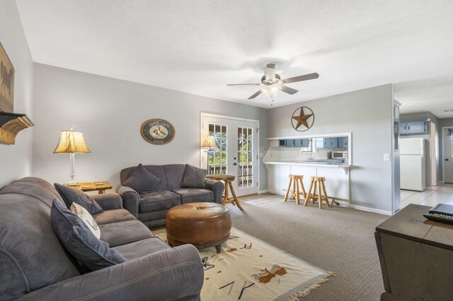 carpeted living room with ceiling fan and french doors