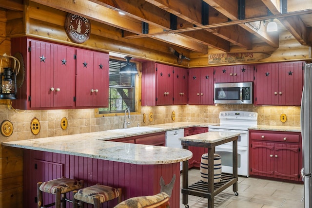 kitchen with sink, light stone counters, kitchen peninsula, white appliances, and backsplash