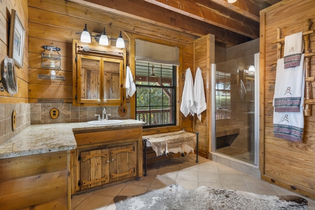 bathroom with tile patterned flooring, walk in shower, vanity, decorative backsplash, and wood walls