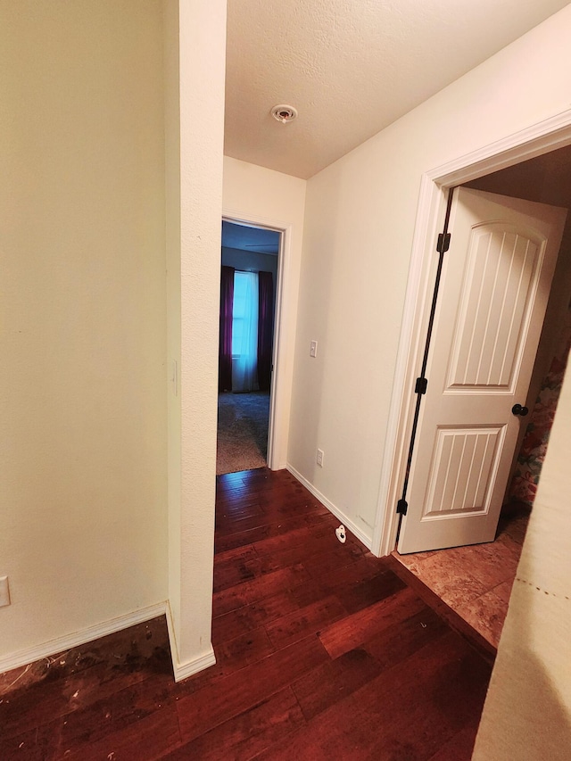 corridor with wood-type flooring and a textured ceiling