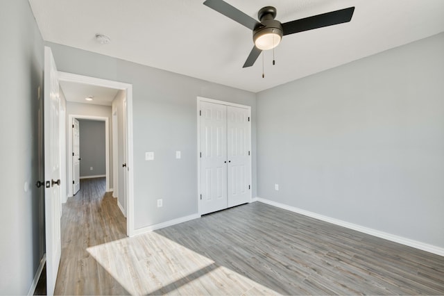 unfurnished bedroom with hardwood / wood-style floors, ceiling fan, and a closet