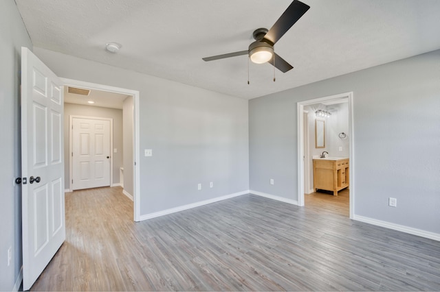 unfurnished bedroom featuring ensuite bath, ceiling fan, sink, wood-type flooring, and a textured ceiling