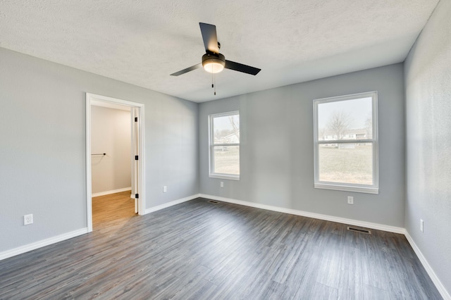 unfurnished room featuring dark hardwood / wood-style floors, ceiling fan, and a textured ceiling