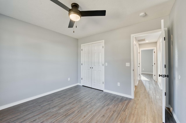 unfurnished bedroom featuring hardwood / wood-style flooring, ceiling fan, a textured ceiling, and a closet