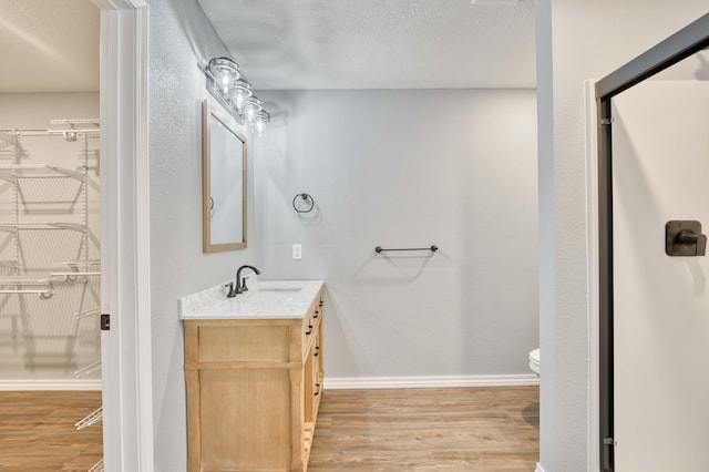 bathroom with wood-type flooring, vanity, a textured ceiling, and toilet