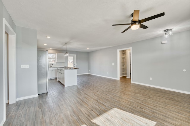 unfurnished living room with ceiling fan with notable chandelier, hardwood / wood-style floors, a textured ceiling, and sink