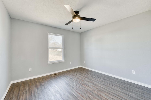 spare room featuring ceiling fan, dark wood-type flooring, and a textured ceiling