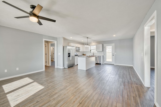 unfurnished living room with a textured ceiling, hardwood / wood-style floors, and ceiling fan with notable chandelier