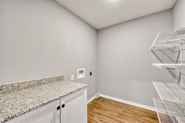 washroom featuring hookup for a washing machine, light hardwood / wood-style floors, a textured ceiling, and hookup for an electric dryer