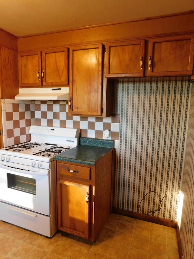 kitchen featuring light tile patterned floors, white range with gas cooktop, and tasteful backsplash