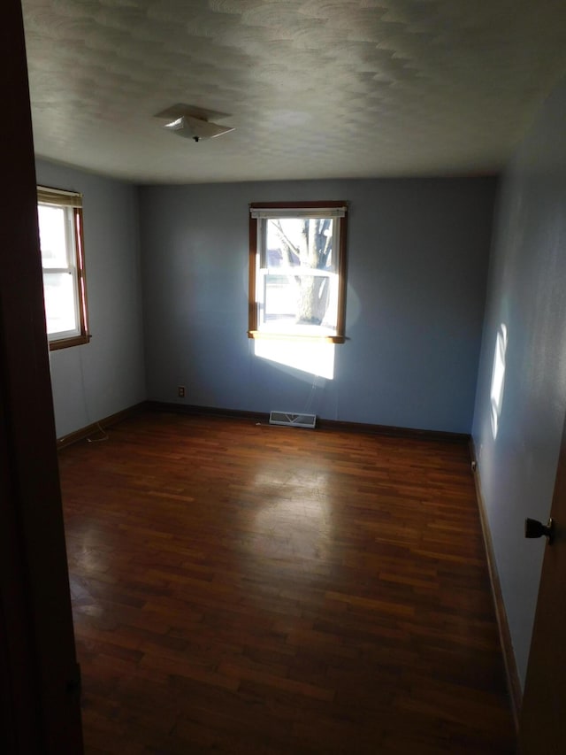 unfurnished room with dark wood-type flooring