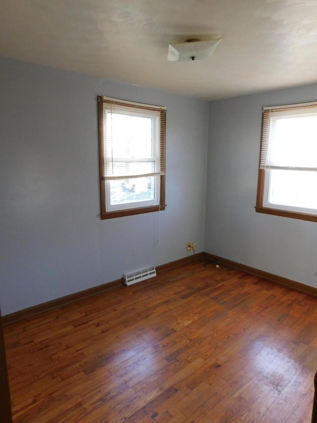 empty room with dark hardwood / wood-style flooring and plenty of natural light