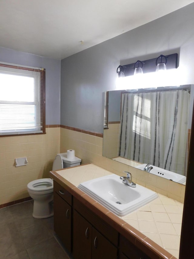 bathroom featuring tile patterned flooring, vanity, toilet, and tile walls