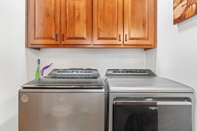 clothes washing area featuring cabinets and independent washer and dryer