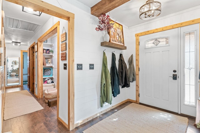 foyer entrance with beamed ceiling, dark wood-type flooring, a healthy amount of sunlight, and wood walls