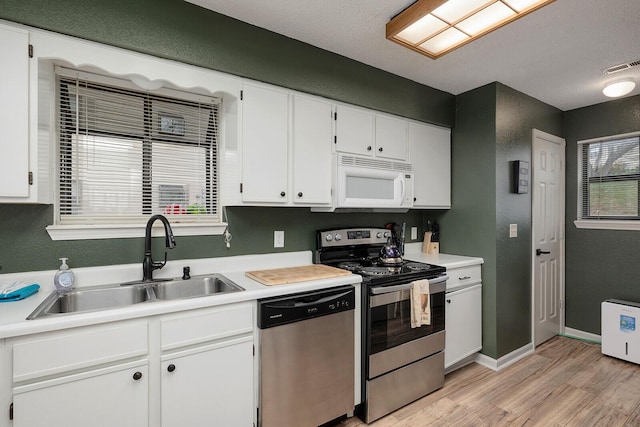 kitchen featuring white cabinets, sink, a textured ceiling, light hardwood / wood-style floors, and stainless steel appliances