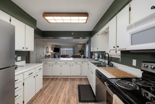 kitchen with appliances with stainless steel finishes, light wood-type flooring, and white cabinetry