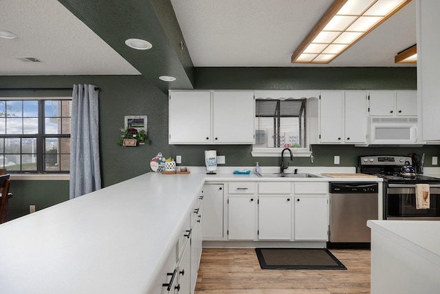 kitchen featuring white cabinets, sink, appliances with stainless steel finishes, and light hardwood / wood-style flooring