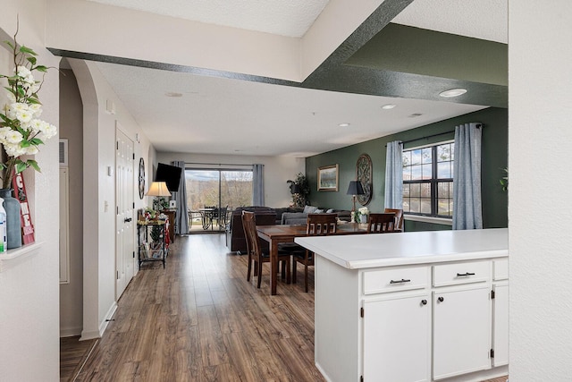 kitchen with white cabinets, a textured ceiling, kitchen peninsula, and dark wood-type flooring