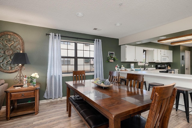 dining room featuring a textured ceiling, light hardwood / wood-style floors, and sink