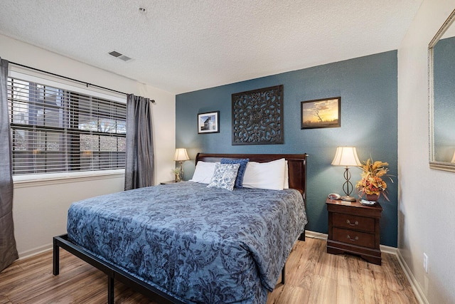 bedroom with light wood-type flooring and a textured ceiling