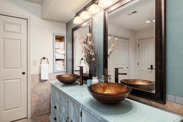 bathroom featuring a textured ceiling, vanity, tile patterned floors, and tile walls