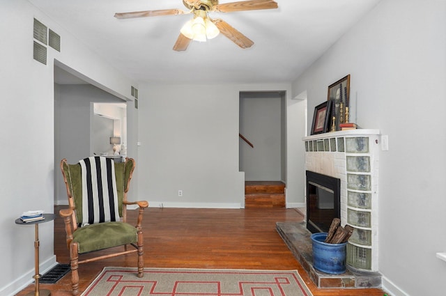 sitting room with a fireplace, hardwood / wood-style flooring, and ceiling fan