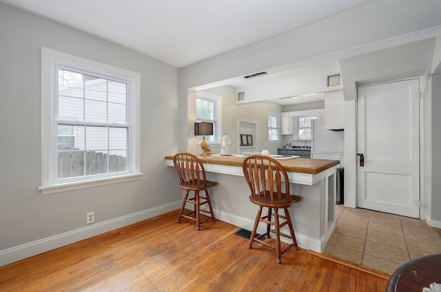 kitchen featuring white cabinets, light wood-type flooring, a breakfast bar area, and kitchen peninsula